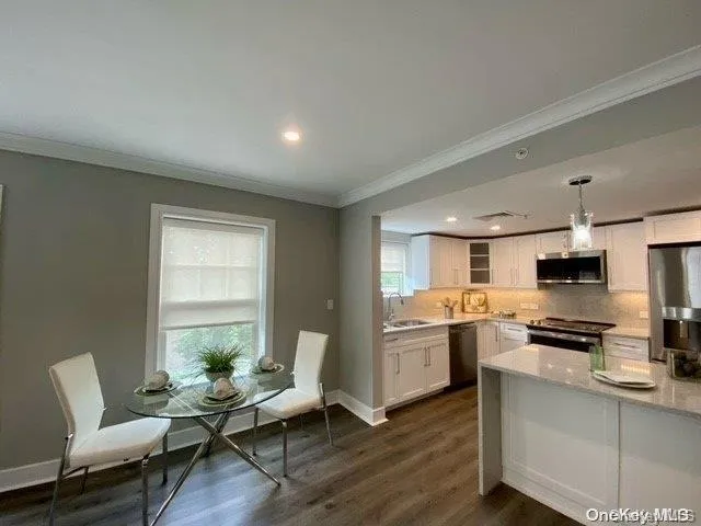 a living room with stainless steel appliances furniture and a wooden floor