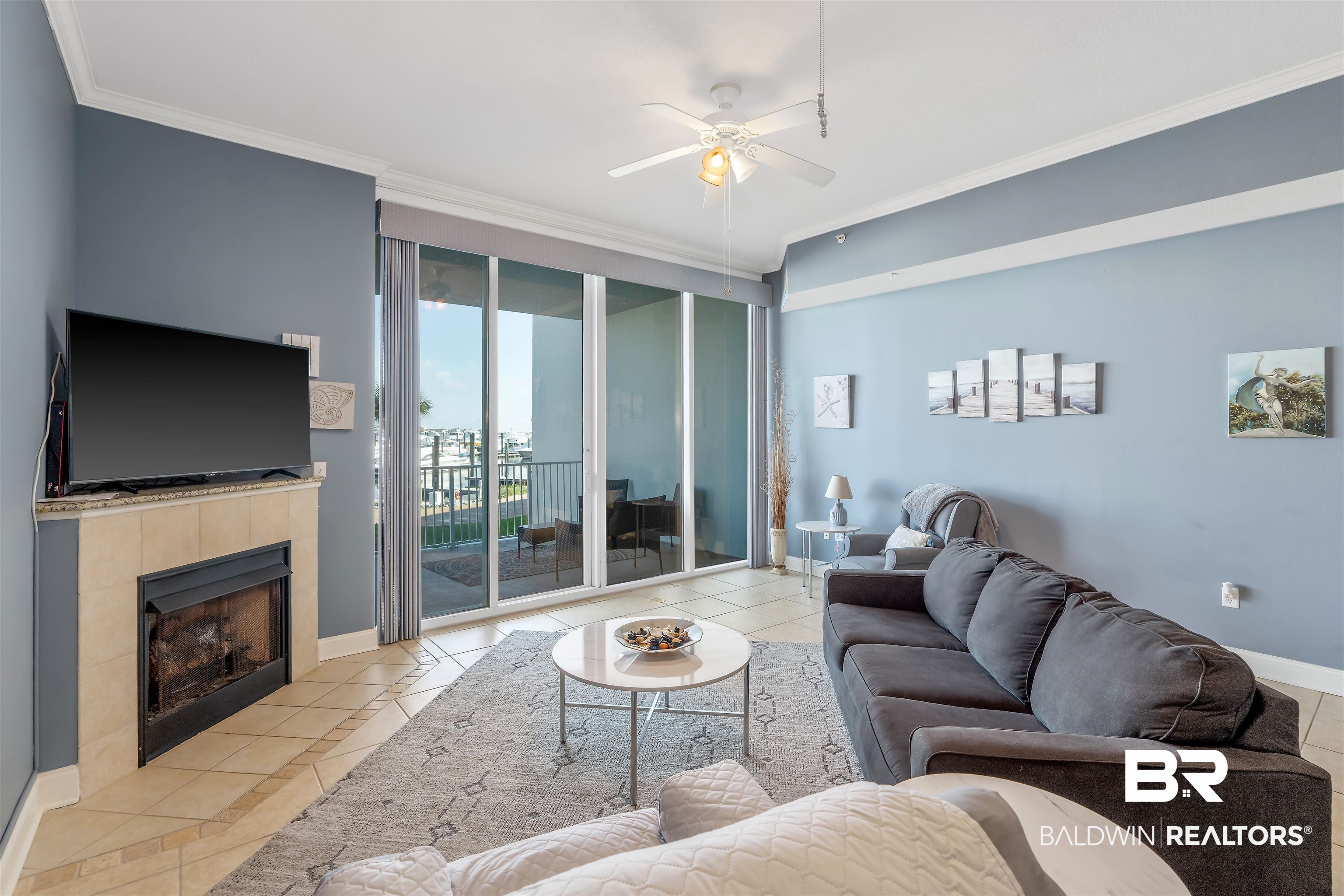 27800 Canal Road, Unit 113 Orange Beach, AL 36561 - Photo 6 of 35 Living area with light tile patterned floors, crown molding, a ceiling fan, a tile fireplace, and expansive windows