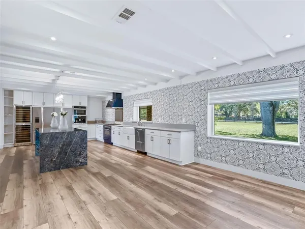 a view of empty room with wooden floor and kitchen view