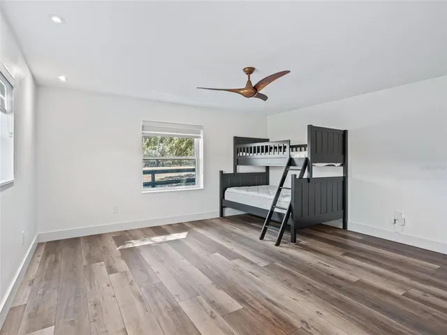 a view of empty room with wooden floor and fan