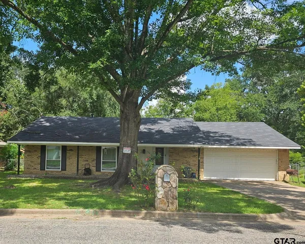 a front view of a house with a garden and tree