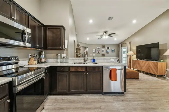 a kitchen with stainless steel appliances granite countertop a stove top oven a sink dishwasher and a microwave oven with wooden floor