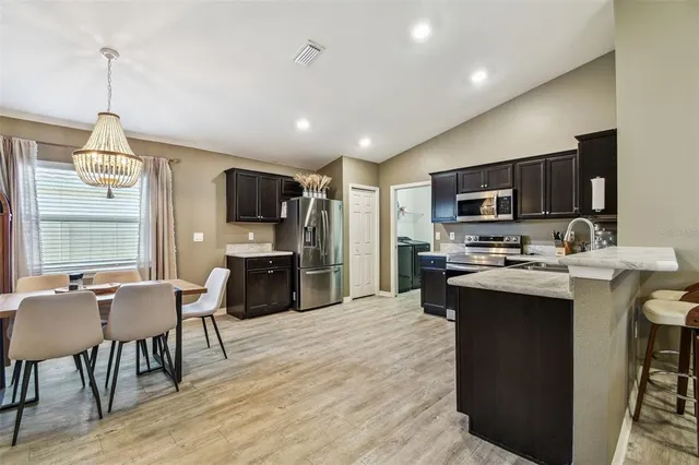 a kitchen with stainless steel appliances a microwave sink stove refrigerator and dining table