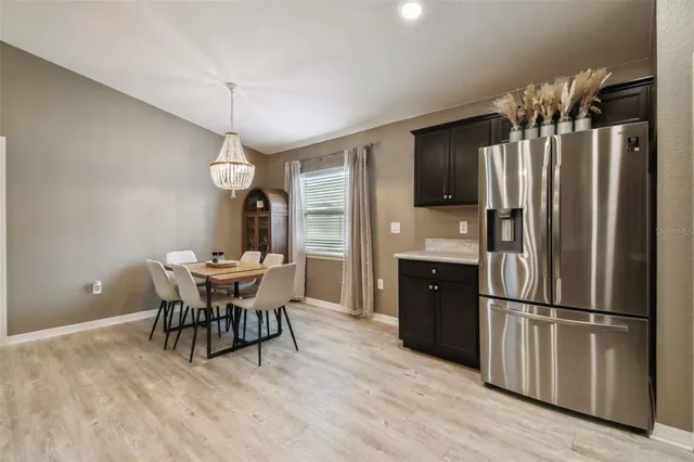 a kitchen with stainless steel appliances a dining table chairs refrigerator and microwave