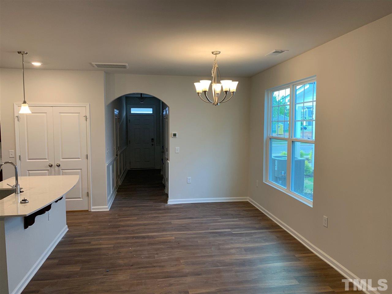 6141 Beale Loop, Unit 57 CARLTON Raleigh, NC 27616 - Photo 5 of 9 an empty room with wooden floor and mirror
