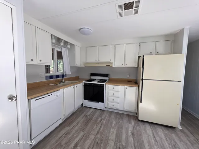a kitchen with granite countertop white cabinets and white appliances