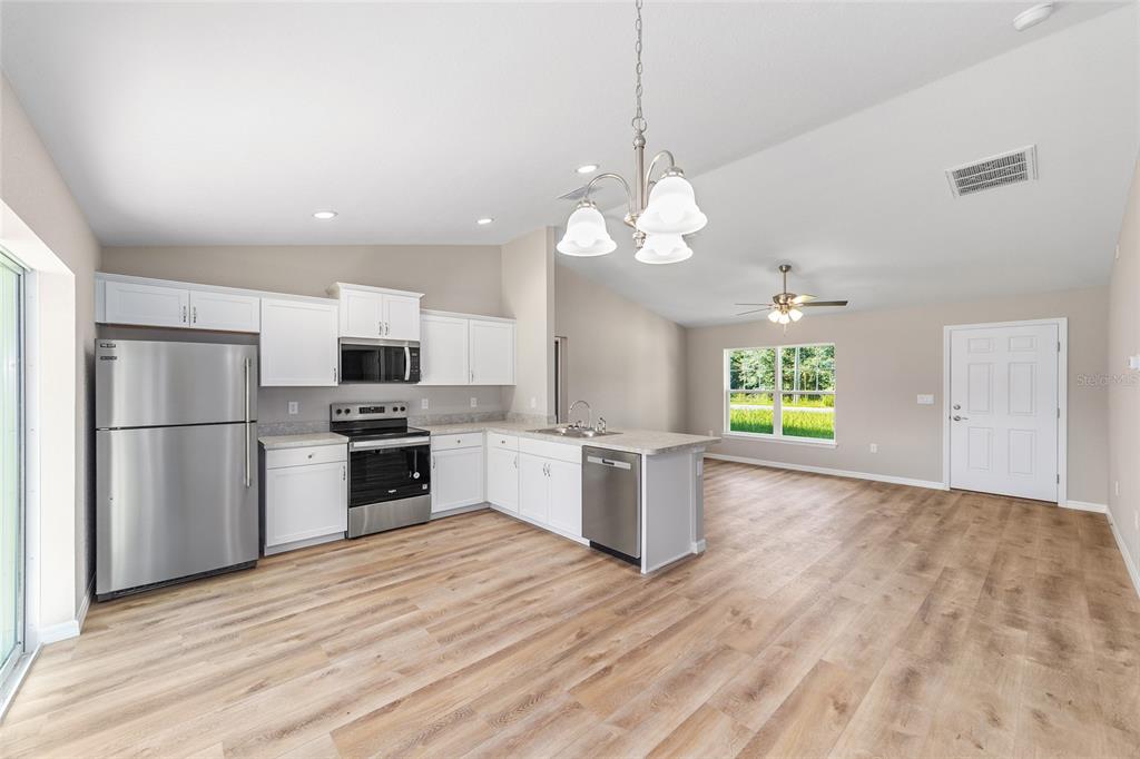 17590 Southwest 112th Place Dunnellon, FL 34432 - Photo 15 of 31 a kitchen with stainless steel appliances granite countertop a refrigerator a stove a sink dishwasher a microwave oven with white cabinets and wooden floor