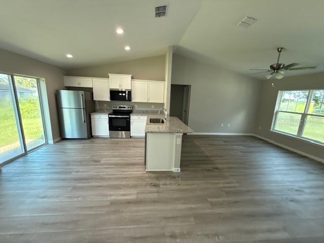17590 Southwest 112th Place Dunnellon, FL 34432 - Photo 5 of 31 an empty room with wooden floor and a kitchen