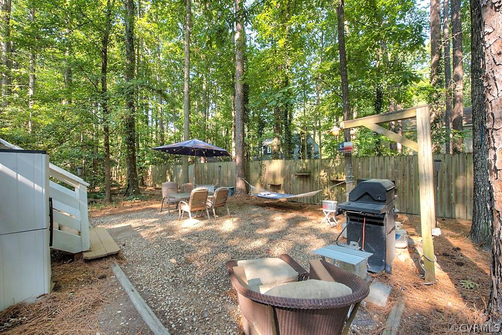 13608 Hunts Bridge Road Midlothian, VA 23112 - Photo 46 of 50 a view of a patio with table and chairs under an umbrella with large trees