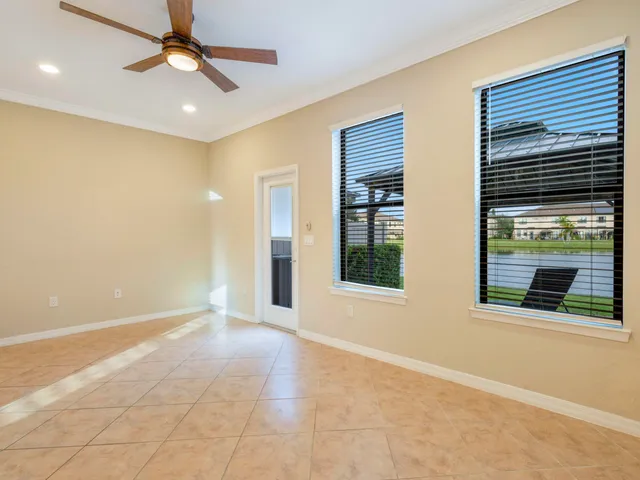 a view of an empty room with window and chandelier fan