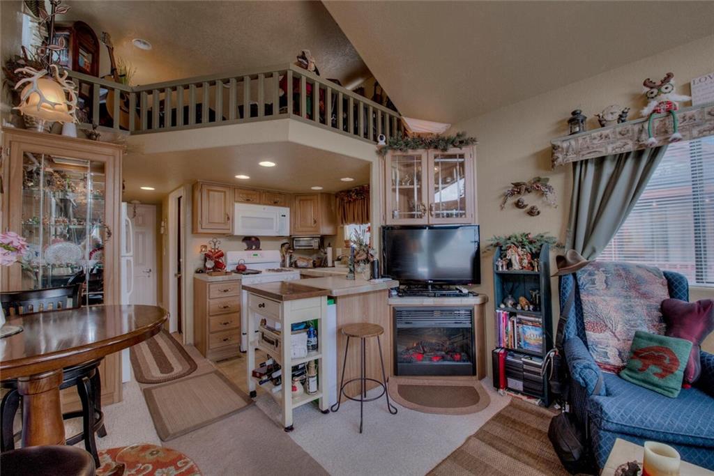 92 Sunshine Loop Fairplay, CO 80440 - Photo 13 of 35 a kitchen with stainless steel appliances kitchen island granite countertop a refrigerator oven a sink a dining table and chairs with wooden floor
