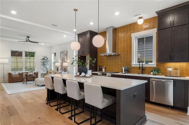 a large white kitchen with a large island oven a stove a sink a dining table and chairs