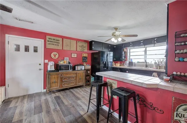 a kitchen with stainless steel appliances granite countertop a stove a refrigerator and a dining table with wooden floor