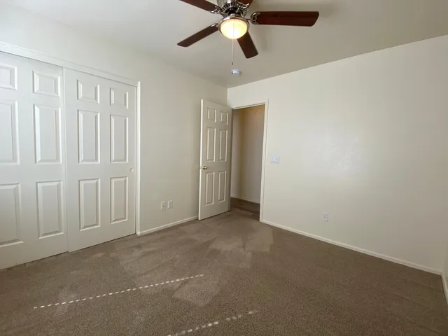 an empty room with a ceiling fan and carpet