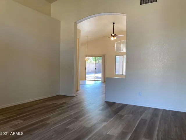 a view of an empty room with wooden floor and a mirror