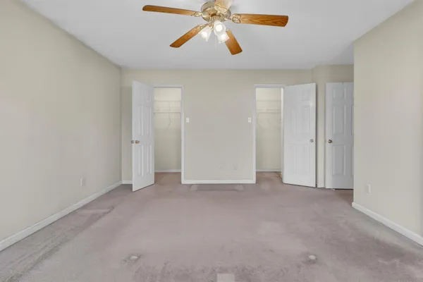 a view of an empty room and chandelier fan
