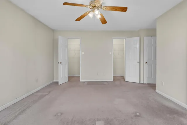 a view of an empty room and chandelier fan