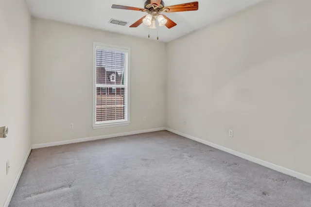 an empty room with a ceiling fan and a window