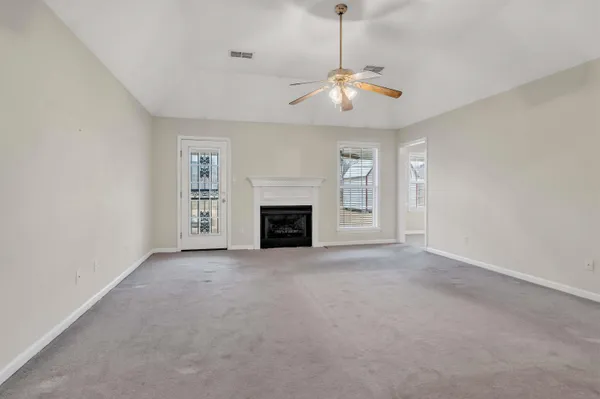 an empty room with fireplace chandelier fan and windows