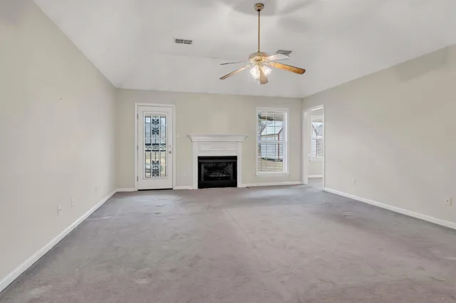an empty room with fireplace chandelier fan and windows