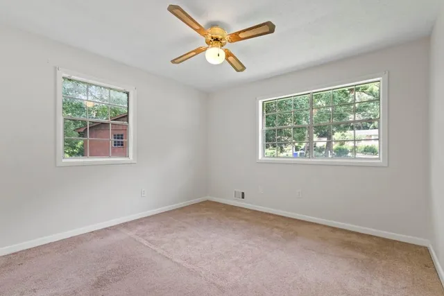 an empty room with a window and a fan