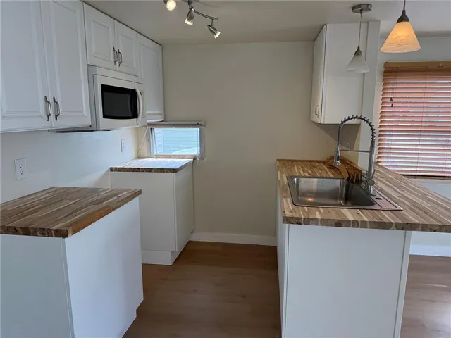 a kitchen with granite countertop a sink and a stove top oven with wooden floor