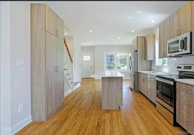a large kitchen with cabinets wooden floor and stainless steel appliances