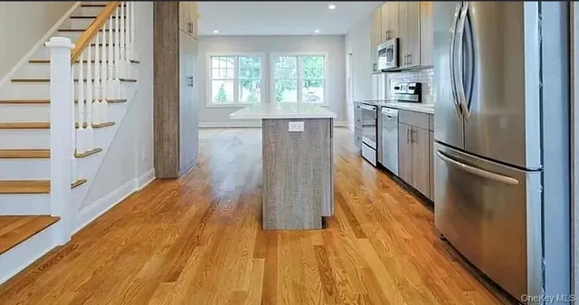 a kitchen with a refrigerator a sink and dishwasher with wooden floor