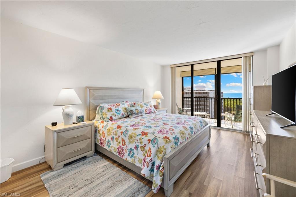 11 Bluebill Avenue, Unit 702 Naples, FL 34108 - Photo 13 of 35 a bedroom with a bed and a flat tv screen on dresser