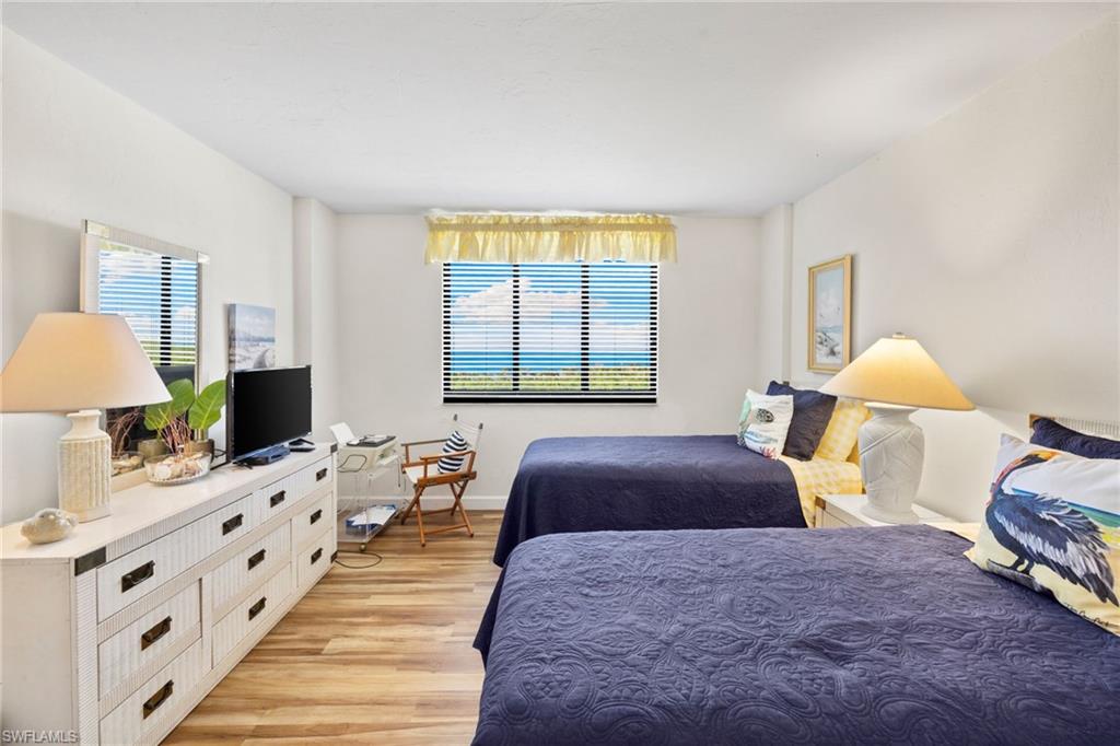 11 Bluebill Avenue, Unit 702 Naples, FL 34108 - Photo 18 of 35 a bedroom with a bed a lamp and a flat screen tv