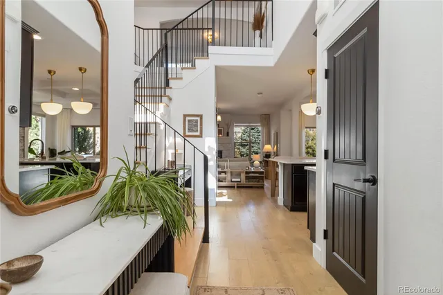 a hallway with a dining table a chandelier a mirror and a window