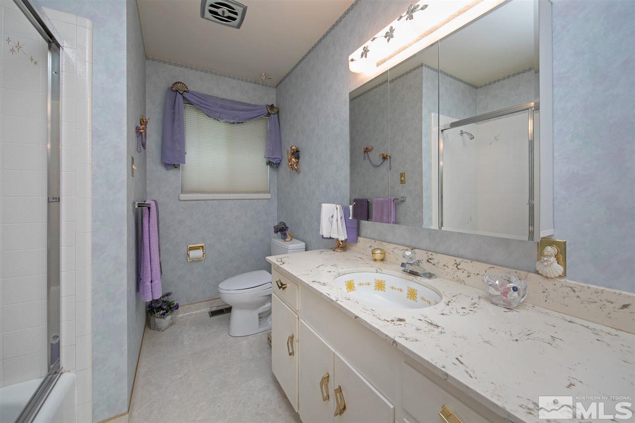 3360 Marthiam Avenue Reno, NV 89509 - Photo 21 of 39 a bathroom with a granite countertop sink a toilet and a mirror