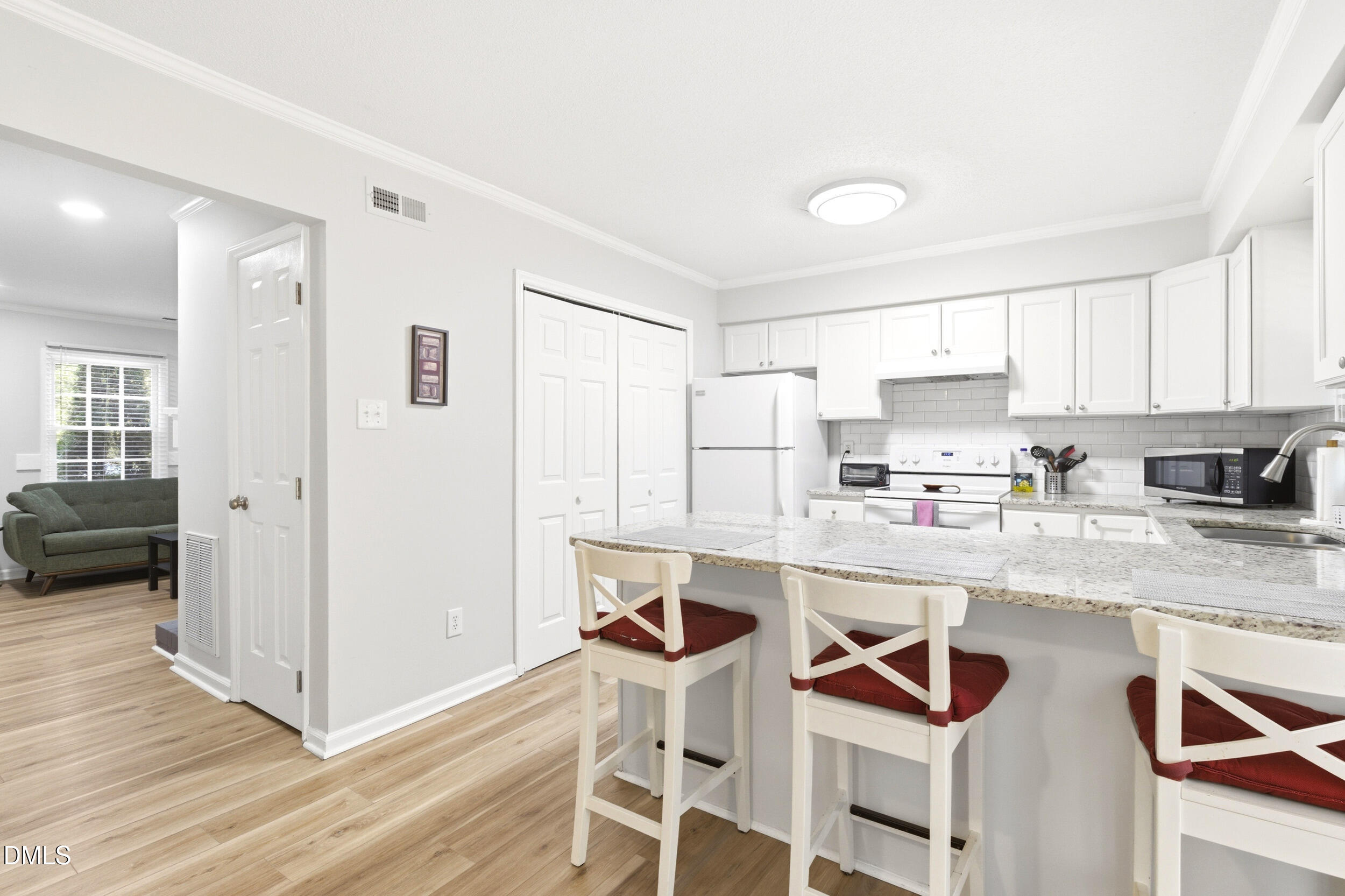 725 Charleston Road Raleigh, NC 27606 - Photo 9 of 27 a kitchen with stainless steel appliances a stove a sink dishwasher a refrigerator with white cabinets and wooden floor