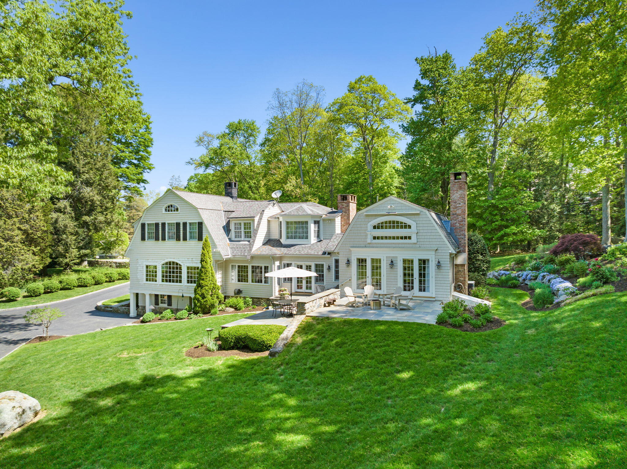 1466 Ponus Ridge Road New Canaan, CT 06840 - Photo 55 of 81 a front view of a house with a yard table and chairs