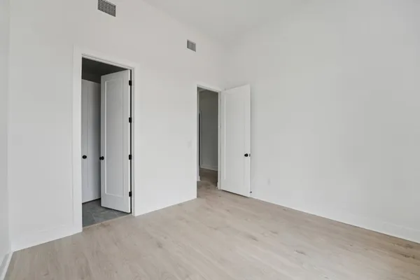 a view of a hallway with wooden floor and a bathroom