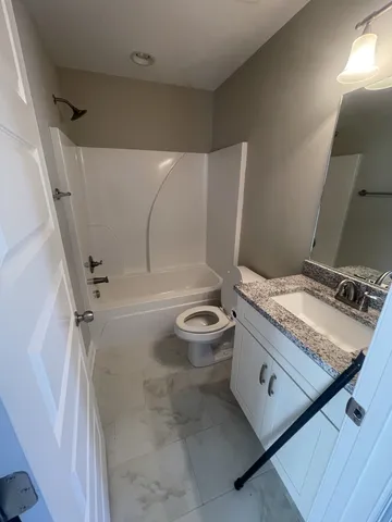 a bathroom with a granite countertop sink a toilet and a shower