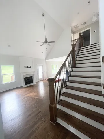 a view of a livingroom with wooden floor a ceiling fan and windows