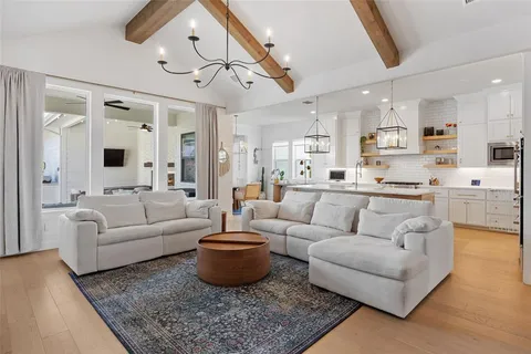 a living room with furniture kitchen view and a chandelier