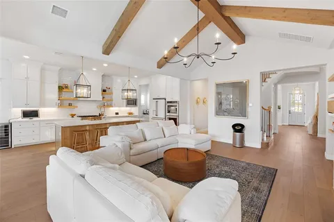 a living room with furniture kitchen view and a chandelier