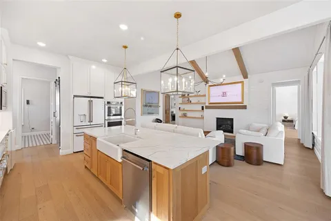 a large kitchen with kitchen island a stove a sink a center island and a wooden floor