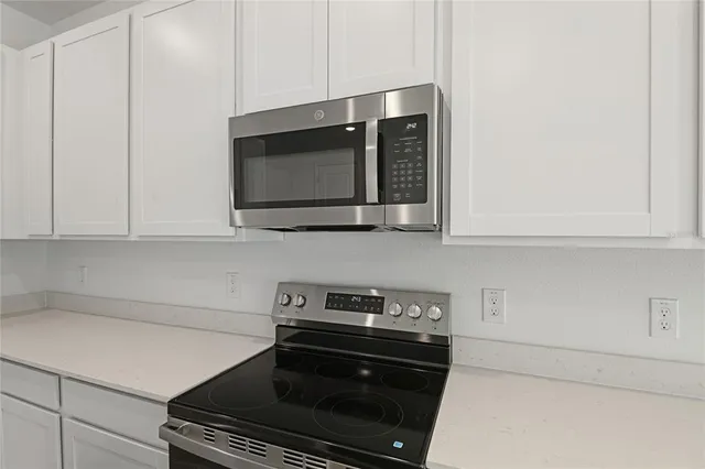 a kitchen with stainless steel appliances white cabinets and a stove top oven
