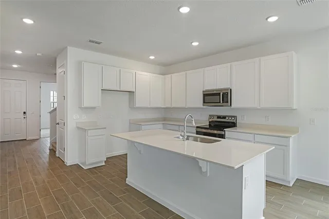a kitchen with a sink a counter top space stainless steel appliances and cabinets