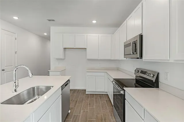 a kitchen that has a sink cabinets counter space and appliances