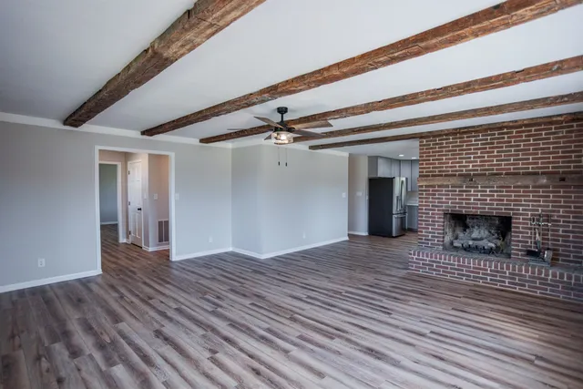 a view of empty room with wooden floor and fireplace
