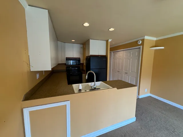 a kitchen with kitchen island a counter top space cabinets a sink and a refrigerator