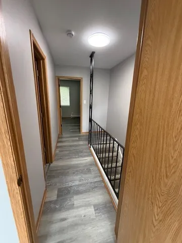 a view of a hallway with wooden floor and staircase