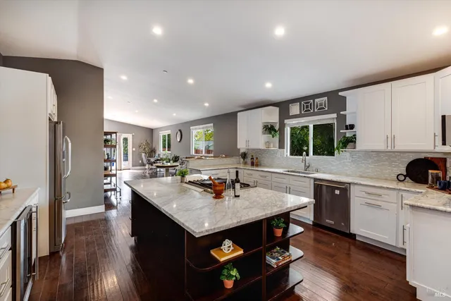 a kitchen with a center island appliances and wooden floor