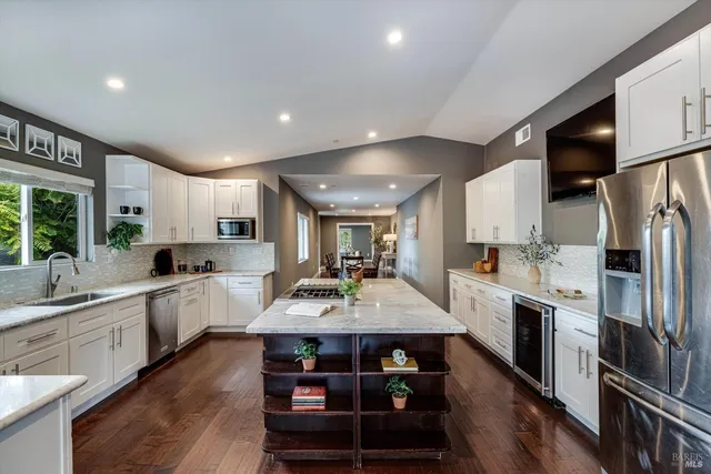 a kitchen with stainless steel appliances granite countertop a dining table chairs stove refrigerator and cabinets