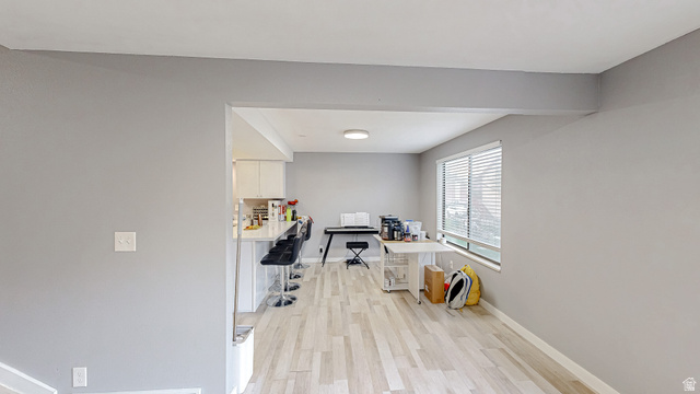 630 1100 West Provo, UT 84601 - Photo 13 of 64 Open-concept living area featuring light wood-finish flooring, a kitchen counter bar, window with blinds, recessed ceiling lighting, and light gray wall finishes