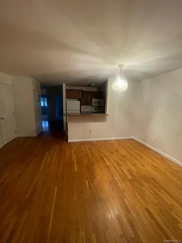 an empty room with wooden floor and chandelier fan
